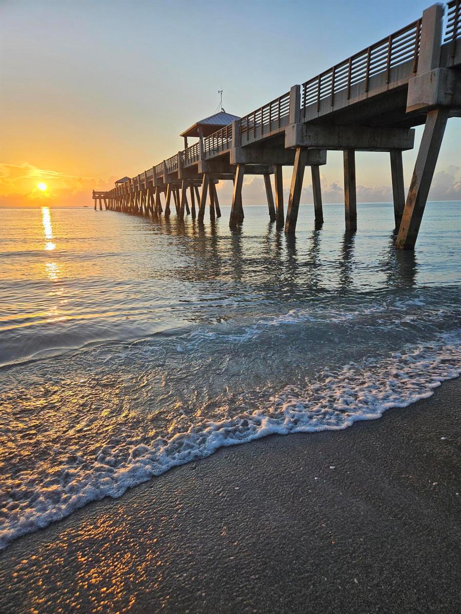 A long concrete pier extends into the ocean at sunrise above a sandy beach — 1206 Mainsail Circle, Jupiter FL 33477, JUPITER, FL