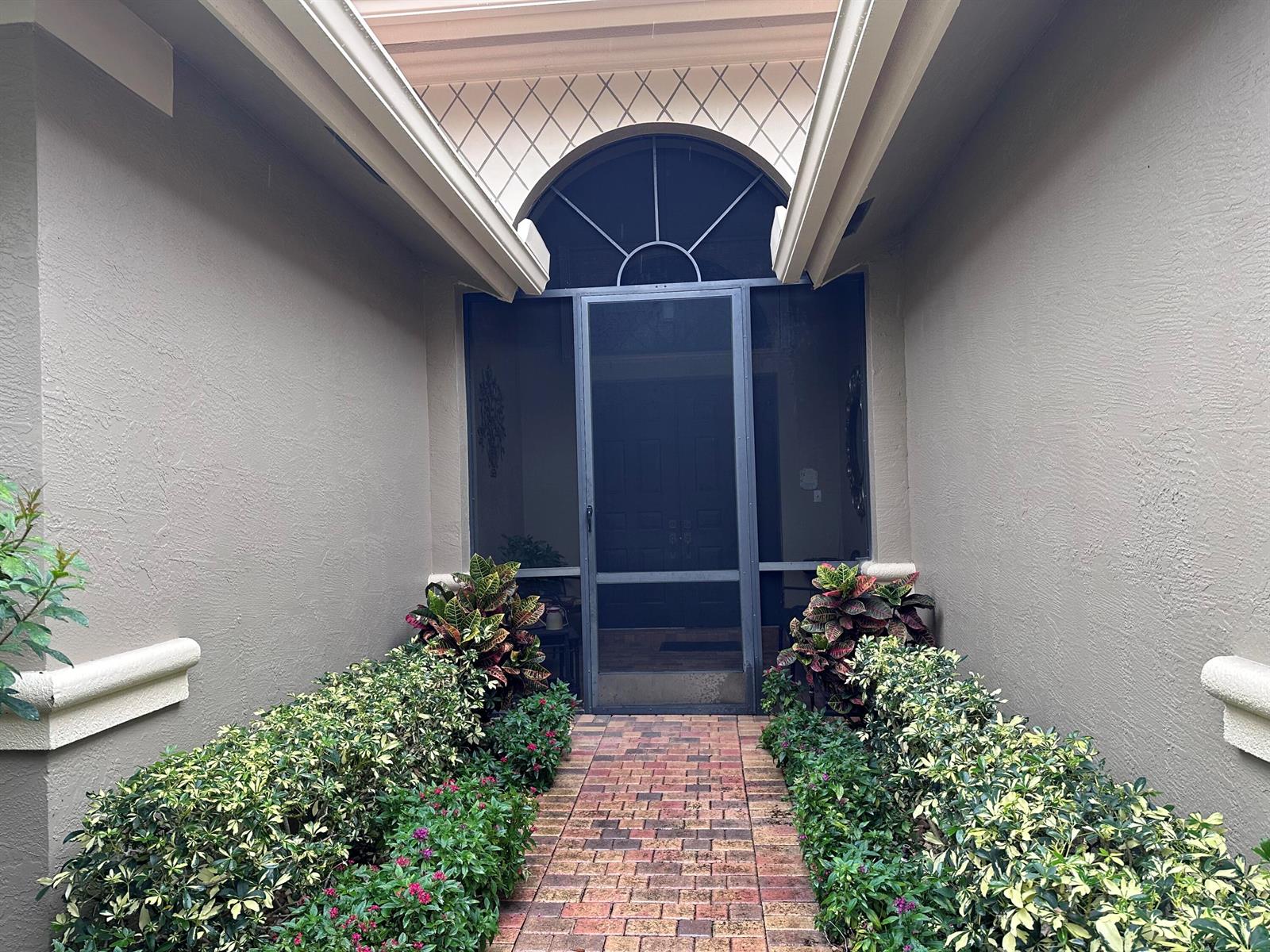 A brick walkway leads to a front entrance with a screen door and arched transom — 8041 E Via Grande, Boynton Beach FL 33437, BOYNTON BEACH, FL