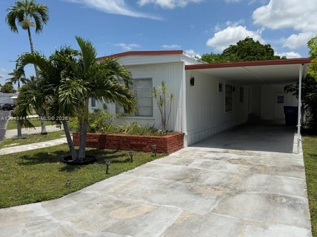 A white mobile home features a brick planter, a palm tree, and an attached carport — 5331 SW 35th ST, Davie FL 33314, DAVIE, FL