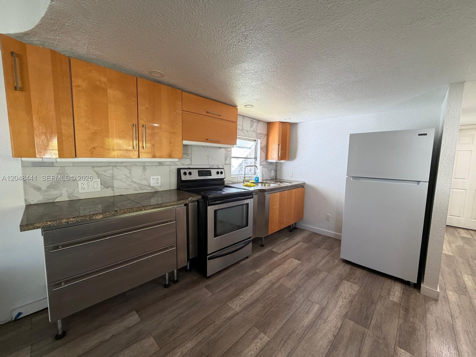 A kitchen features wood-toned upper cabinets, stainless steel lower cabinets, a stove, and a refrigerator — 5331 SW 35th ST, Davie FL 33314, DAVIE, FL