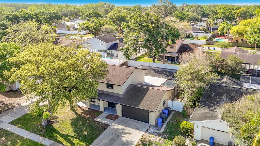 An aerial view shows a two-story house with a dark roof and a screened pool — 4012 BRAESGATE LANE, TAMPA, FL