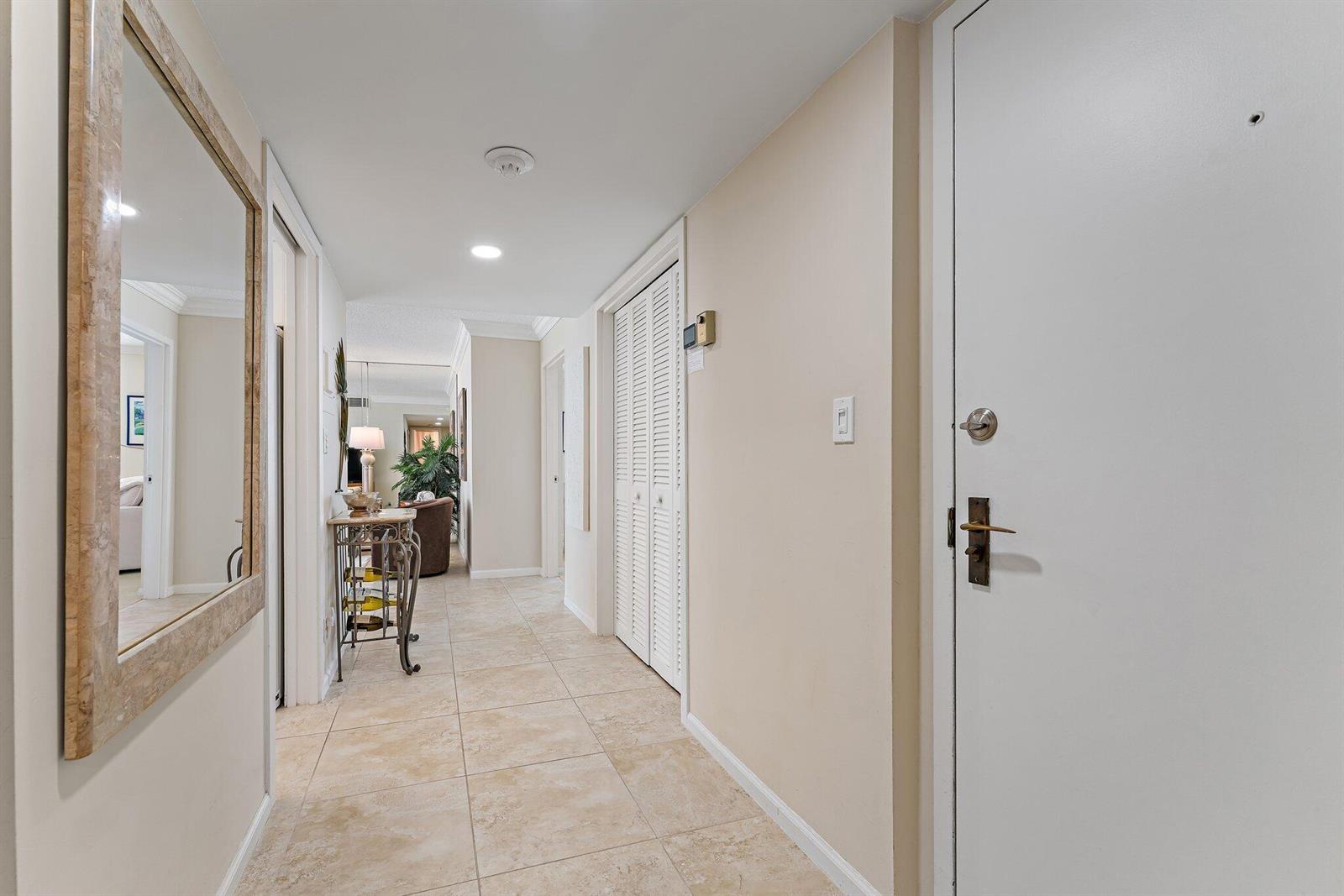 A tiled hallway features a large mirror, a console table, and louvered closet doors — 5480 N Ocean Drive, Singer Island FL 33404, SINGER ISLAND, FL