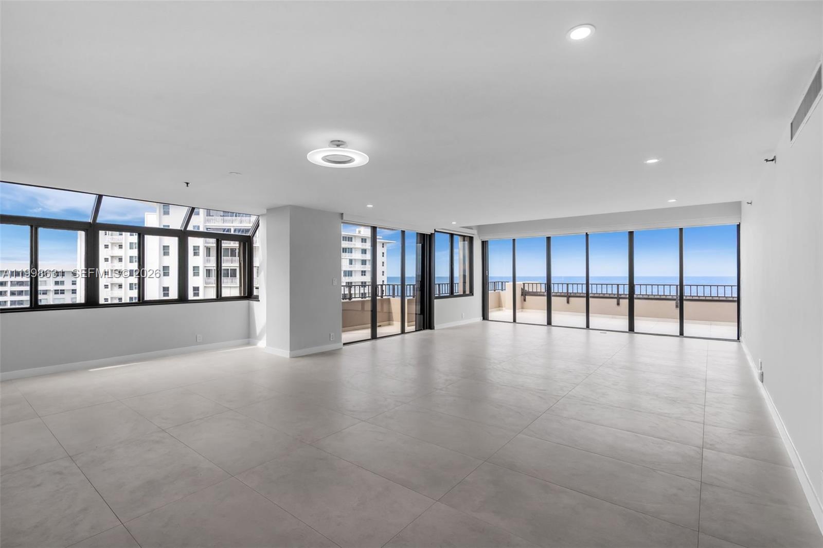 An empty, modern living room features large floor-to-ceiling windows, tile flooring, and a balcony — 251 Crandon Blvd # 1037, Key Biscayne FL 33149, KEY BISCAYNE, FL