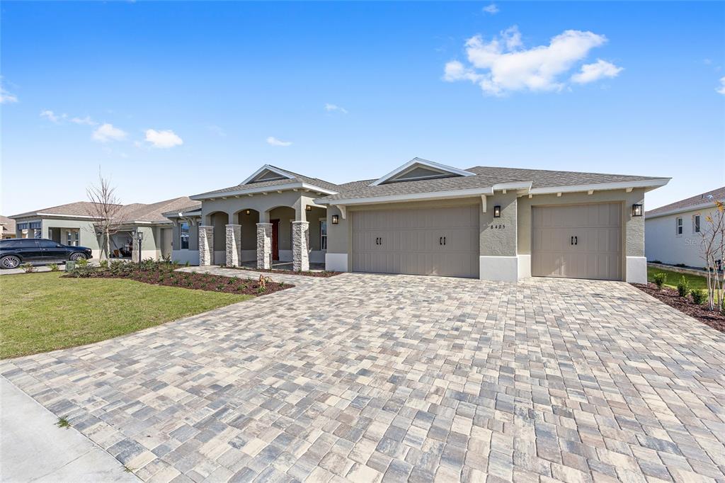 A single-story house features a stone-accented porch, a paved driveway, and a three-car garage — 8425 SW 101ST AVENUE, OCALA, FL