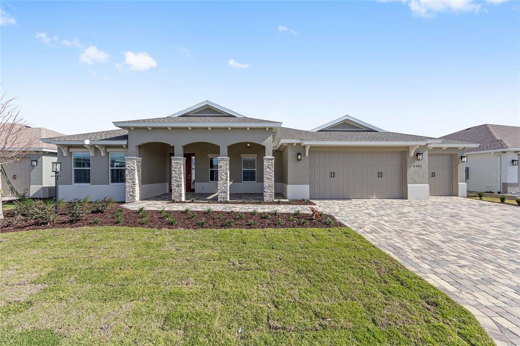 A single-story house with a stone-accented porch, a three-car garage, and a paved driveway — 8425 SW 101ST AVENUE, OCALA, FL