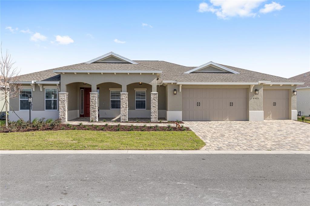 A single-story house with a stone-accented porch, a three-car garage, and a paved driveway — 8425 SW 101ST AVENUE, OCALA, FL