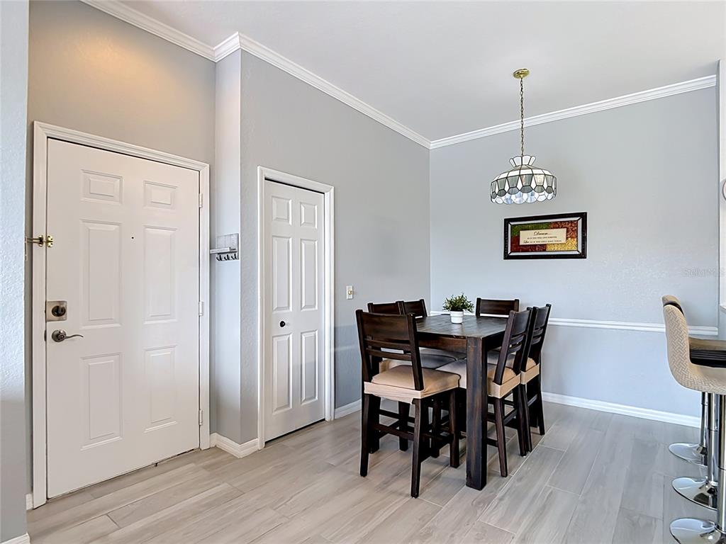 A dining area features a wooden table with chairs, a pendant light, and light flooring — 18107 PEREGRINES PERCH PLACE UNIT 6304, LUTZ, FL