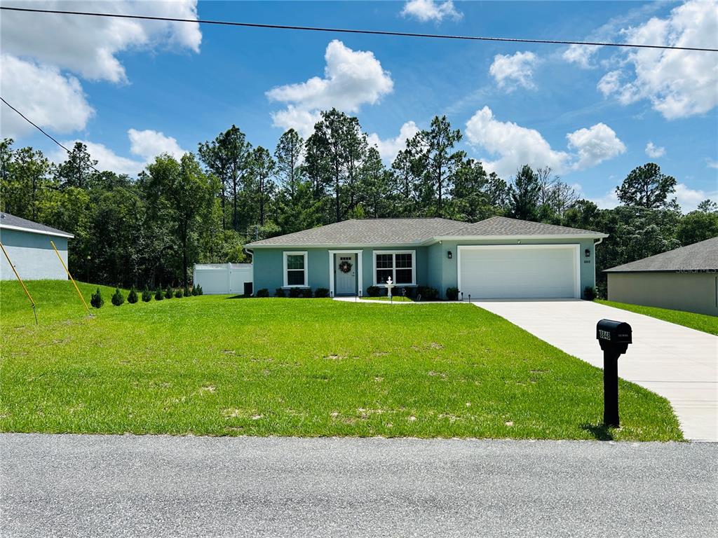 A light blue single-story house with a white garage and a green lawn — 8848 N PARADISEA DRIVE, CITRUS SPRINGS, FL