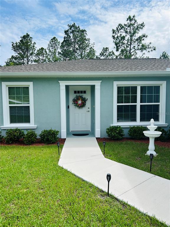 A light blue house exterior features a white front door, two windows, and a walkway — 8848 N PARADISEA DRIVE, CITRUS SPRINGS, FL