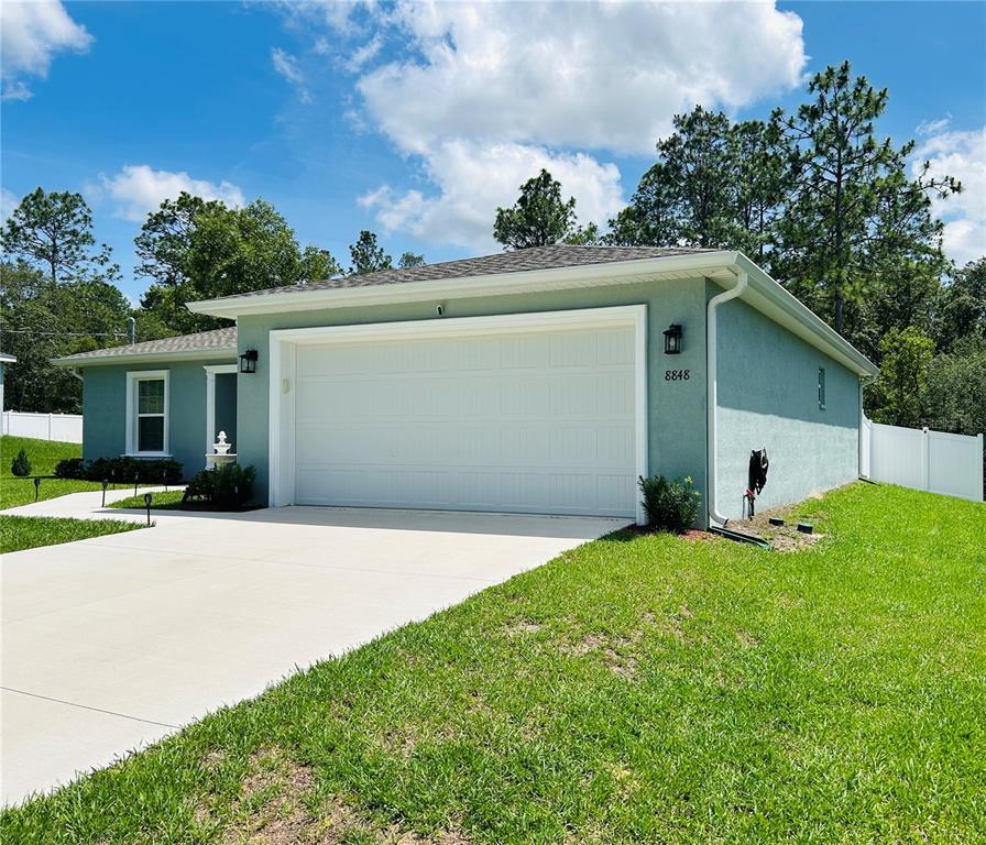 A light blue single-story house with a white garage door and a concrete driveway — 8848 N PARADISEA DRIVE, CITRUS SPRINGS, FL