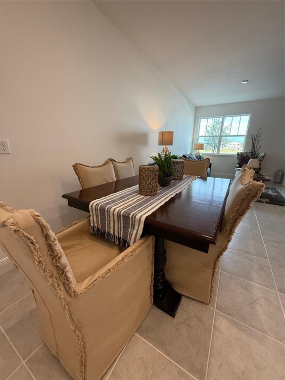 A dining room features a dark wood table with a striped runner and upholstered chairs — 4870 PRAIRIE PRESERVE RUN NW, ST CLOUD, FL