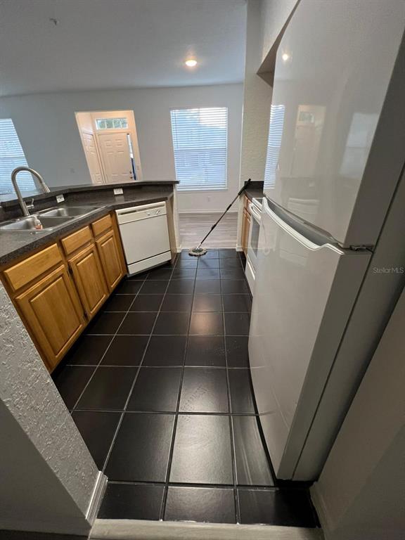 A kitchen features dark tile flooring, light wood cabinets, a white refrigerator, and a dishwasher — 5963 WESTGATE DRIVE UNIT 1414, ORLANDO, FL