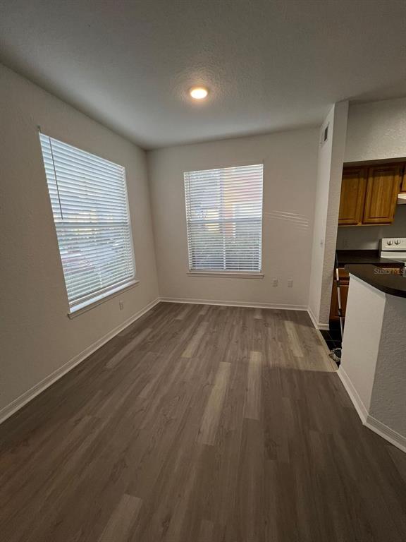 A dining area with wood-look flooring, two windows with blinds, and an adjacent kitchen — 5963 WESTGATE DRIVE UNIT 1414, ORLANDO, FL