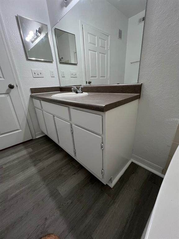 A bathroom vanity with a dark countertop, white cabinets, and a large wall mirror — 5963 WESTGATE DRIVE UNIT 1414, ORLANDO, FL
