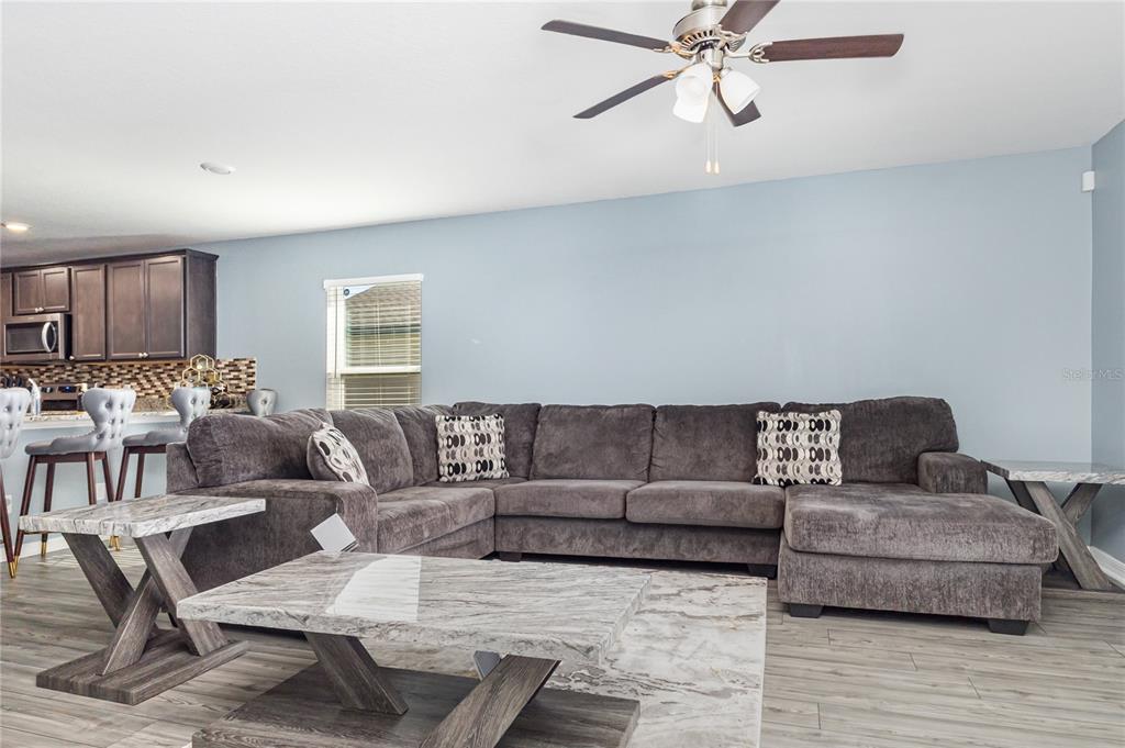 A living room features a large gray sectional sofa, a marble coffee table, and a ceiling fan — 1760 CANAAN LOOP, DUNDEE, FL