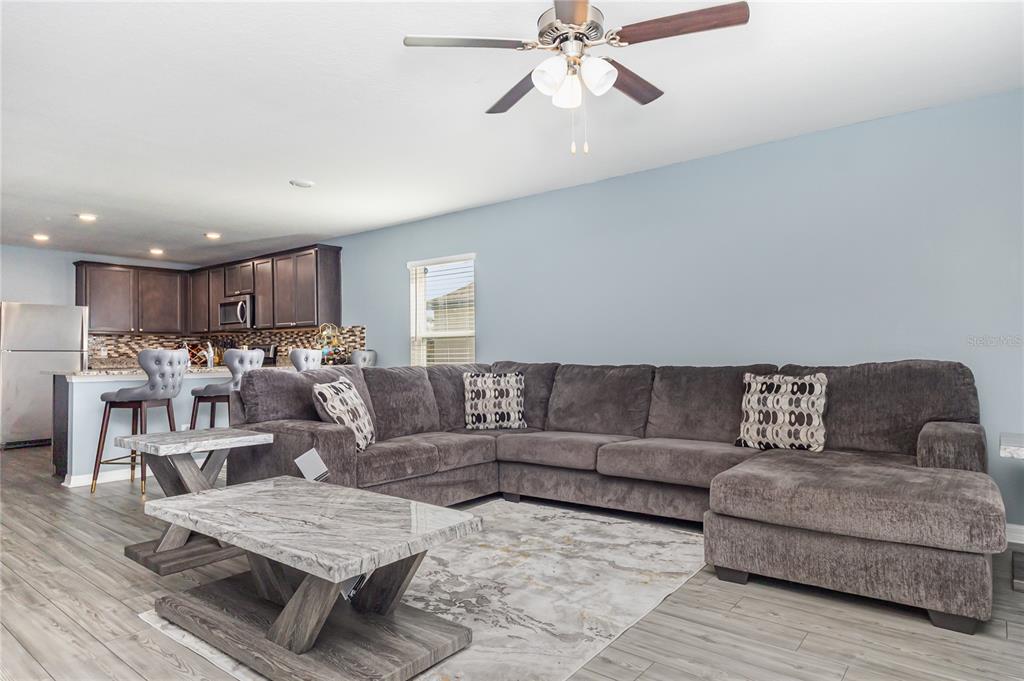 A living room with a gray sectional sofa, marble-topped coffee table, and an open kitchen — 1760 CANAAN LOOP, DUNDEE, FL