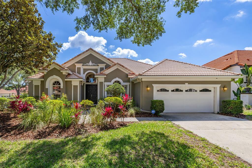 A single-story house with a tile roof, beige stucco exterior, and an attached two-car garage — 1855 VISTA ROYALE BOULEVARD, ORLANDO, FL