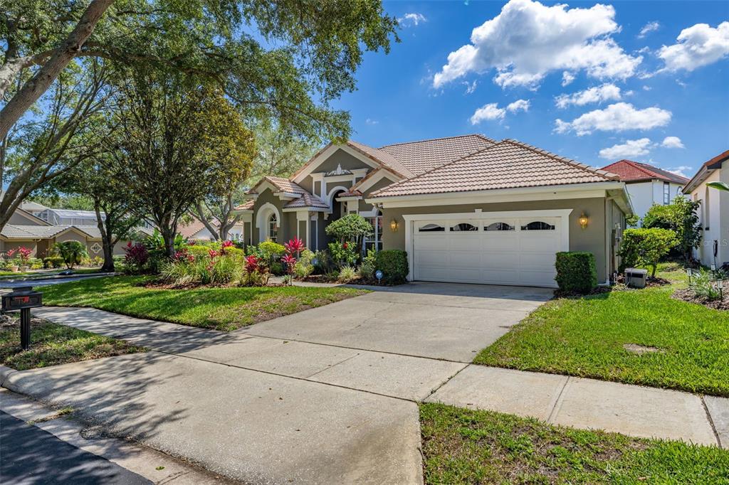 A single-story suburban house with a tan exterior, a two-car garage, and a tiled roof — 1855 VISTA ROYALE BOULEVARD, ORLANDO, FL