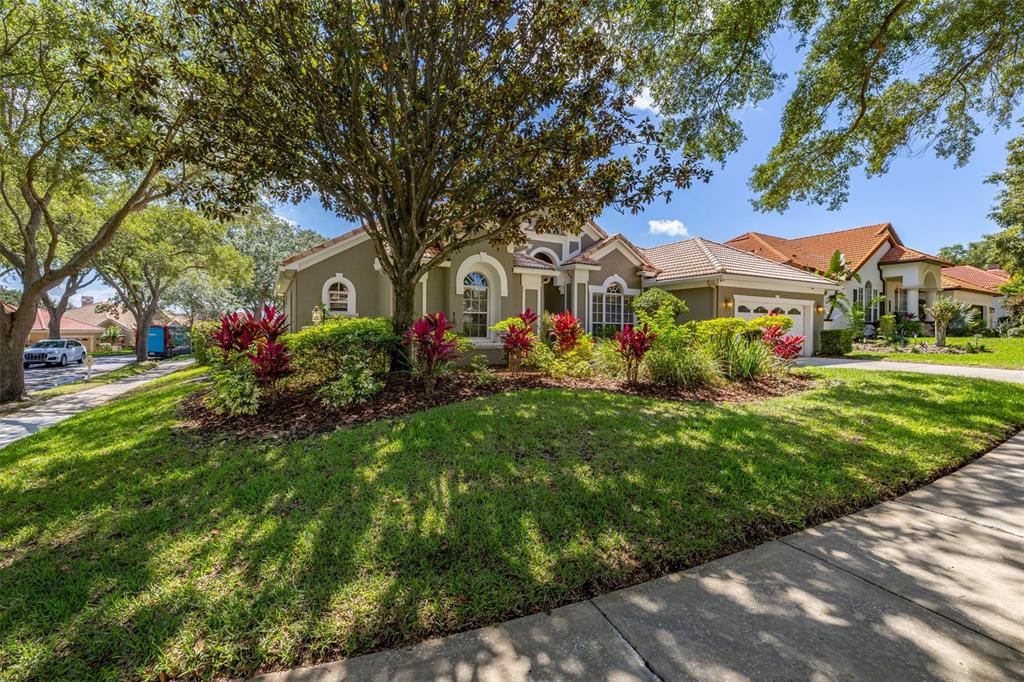 A single-story house with a tiled roof, a large tree, and landscaping in the front yard — 1855 VISTA ROYALE BOULEVARD, ORLANDO, FL