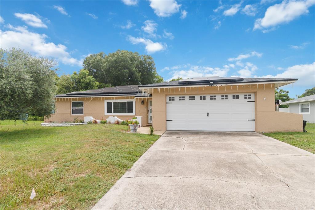 A single-story tan house with a white garage door, solar panels, and a concrete driveway — 5316 HALYARD COURT, WINTER PARK, FL