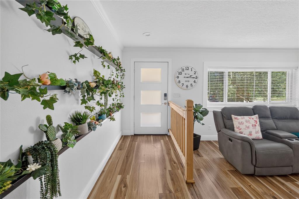 A living room features wood flooring, a white front door, and a wall with tiered shelving — 5316 HALYARD COURT, WINTER PARK, FL