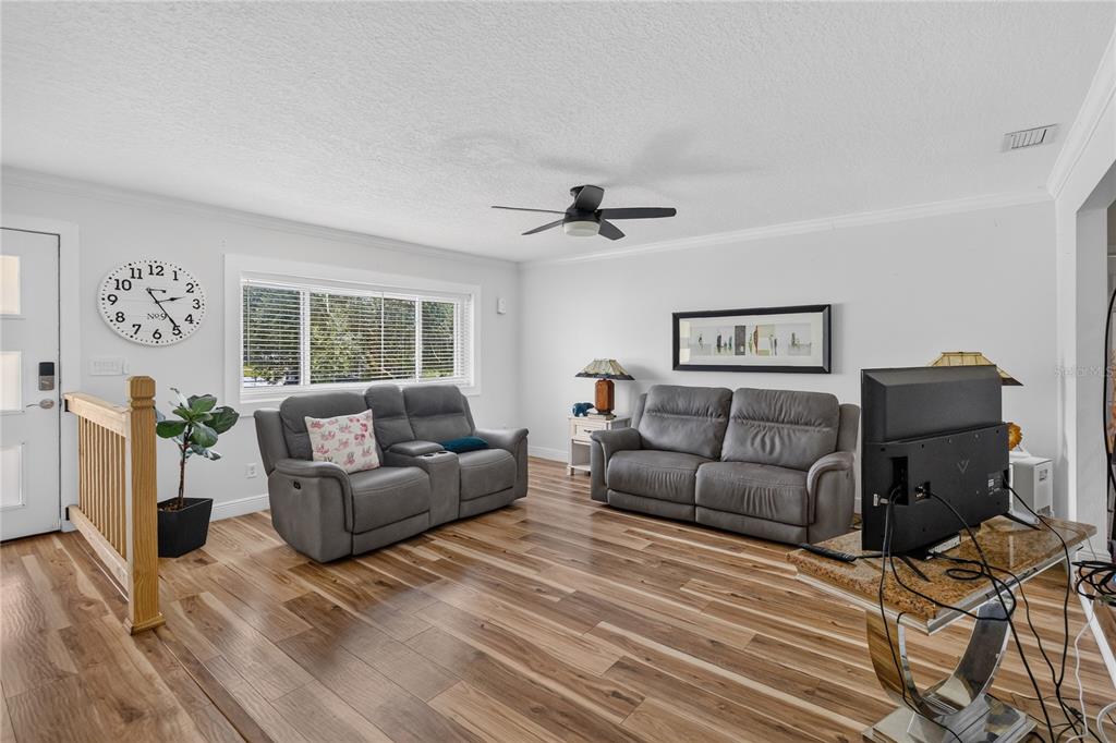 A living room features two gray leather sofas, wood-look flooring, and a large wall clock — 5316 HALYARD COURT, WINTER PARK, FL