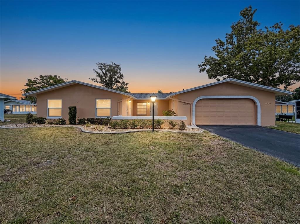A single-story house with a tan exterior, a two-car garage, and a front lawn — 12024 BAYONET LANE UNIT 9GB, NEW PORT RICHEY, FL