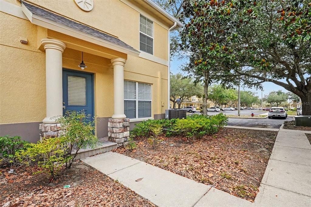 A two-story yellow stucco apartment building features a covered entrance with columns and landscaping — 217 PENMARK STONE PLACE, VALRICO, FL