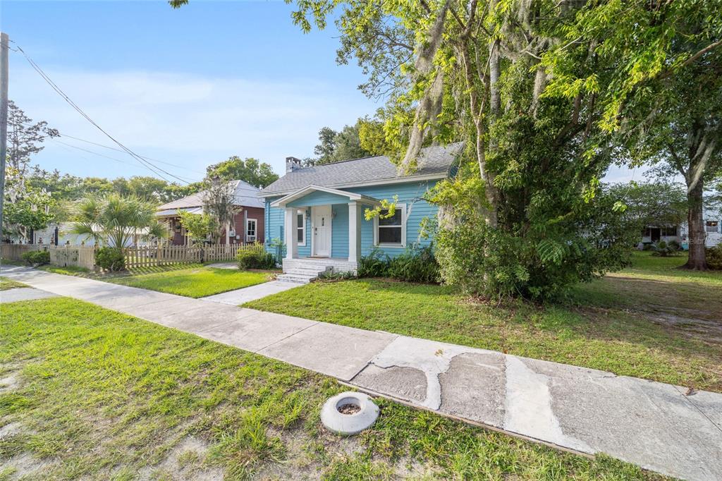 A light blue, single-story house with a front porch sits behind a concrete sidewalk — 20837 WALNUT STREET, DUNNELLON, FL