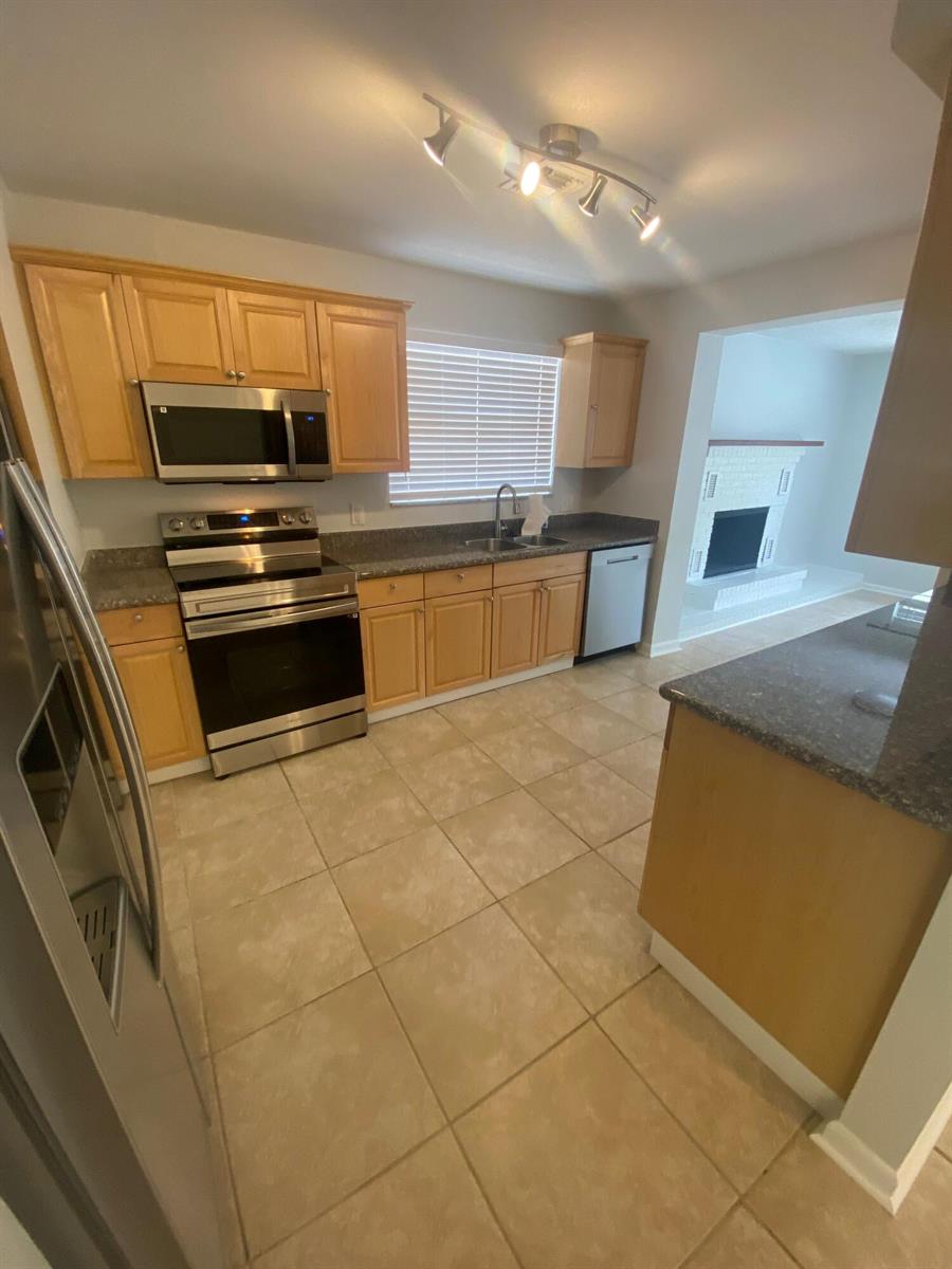 An empty room with light gray walls, recessed lighting, and tan tile flooring — 1317 Willow Road, West Palm Beach FL 33406, WEST PALM BEACH, FL