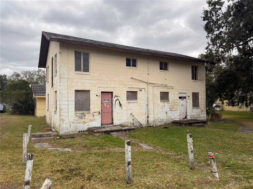 A two-story, weathered concrete block apartment building with boarded-up windows and two exterior doors — 1305 E BAKER STREET, PLANT CITY, FL