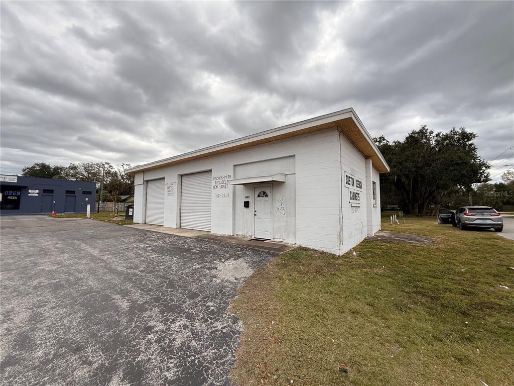 A white, single-story commercial building with two roll-up garage doors and a front entrance — 1305 E BAKER STREET, PLANT CITY, FL