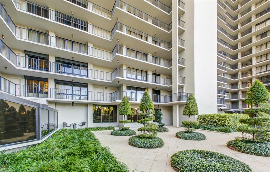 A multi-story apartment building features balconies overlooking a paved courtyard with manicured topiary trees — 3301 BAYSHORE BOULEVARD UNIT 505C, TAMPA, FL