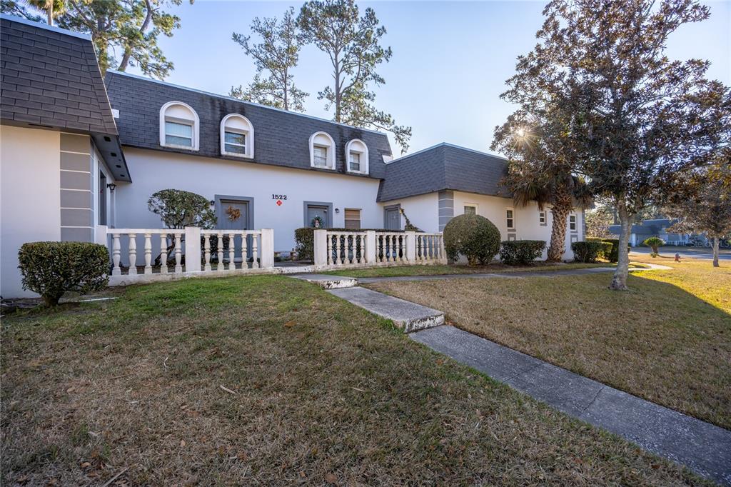 A two-story townhouse exterior features a white facade, dark shingled roof, and a stone railing — 1522 SE 25TH STREET UNIT D, OCALA, FL