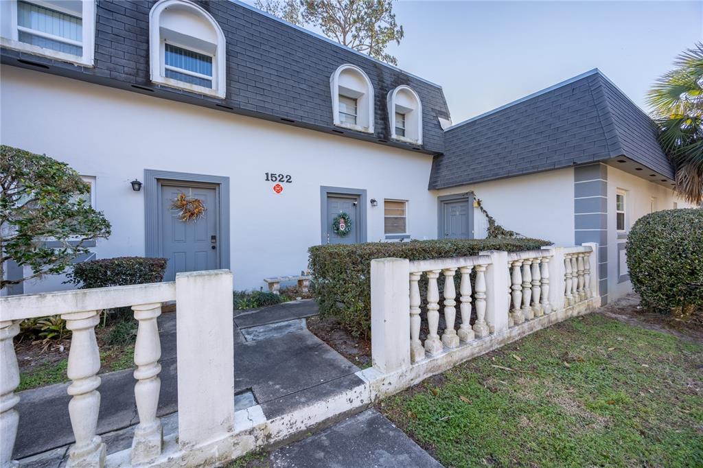 A two-story townhouse exterior features white walls, a dark mansard roof, and a balustrade fence — 1522 SE 25TH STREET UNIT D, OCALA, FL