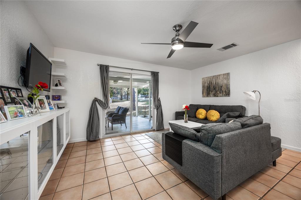 A living room features tile flooring, a gray sectional sofa, and sliding glass doors to a patio — 1522 SE 25TH STREET UNIT D, OCALA, FL