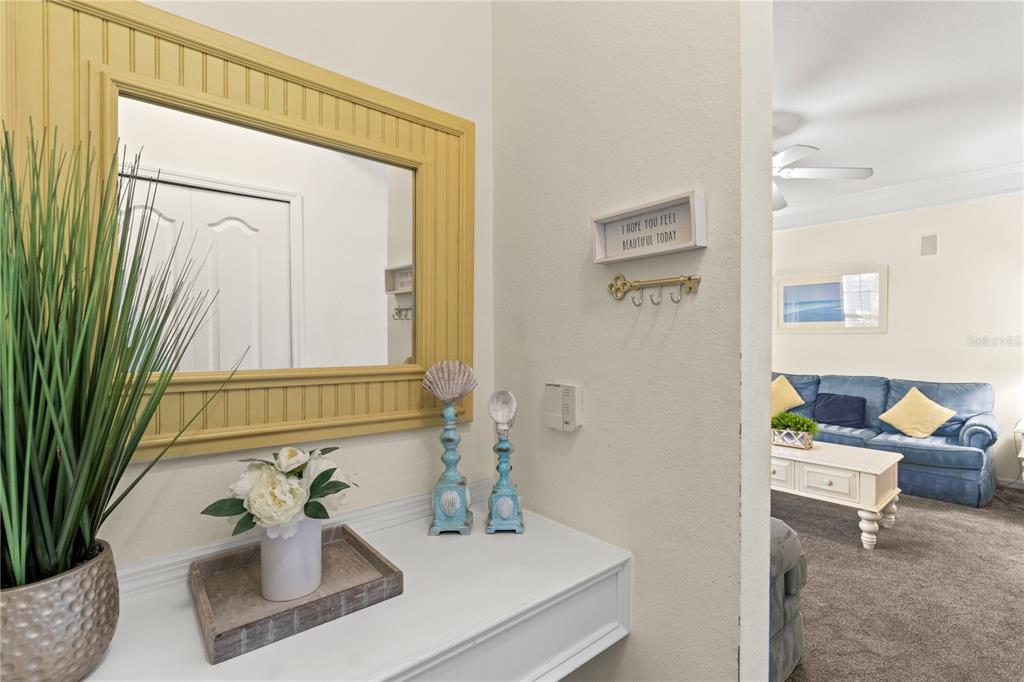 A white entryway console table features a yellow-framed mirror, decorative accents, and a wall-mounted key rack — 3002 BONFIRE BEACH DRIVE UNIT 102, KISSIMMEE, FL