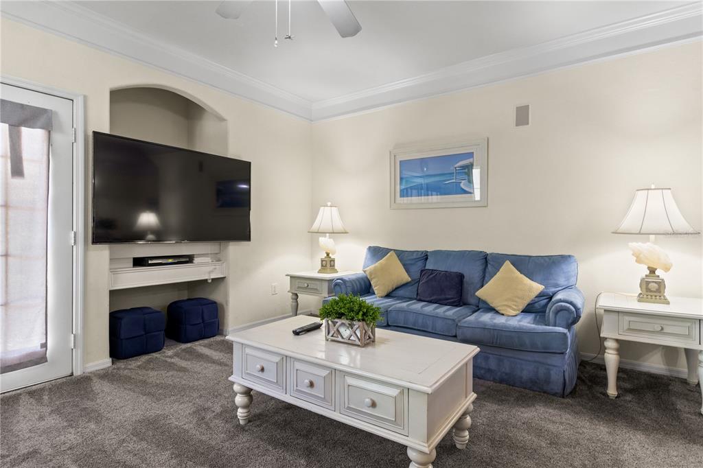 A living room features a blue sofa, a white coffee table, and a wall-mounted television — 3002 BONFIRE BEACH DRIVE UNIT 102, KISSIMMEE, FL