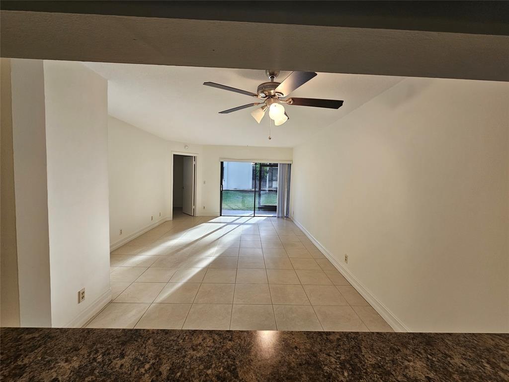 An empty living room with light tile flooring, a ceiling fan, and sliding glass doors — 5583 Courtyard Drive # 5583, Margate FL 33063, MARGATE, FL