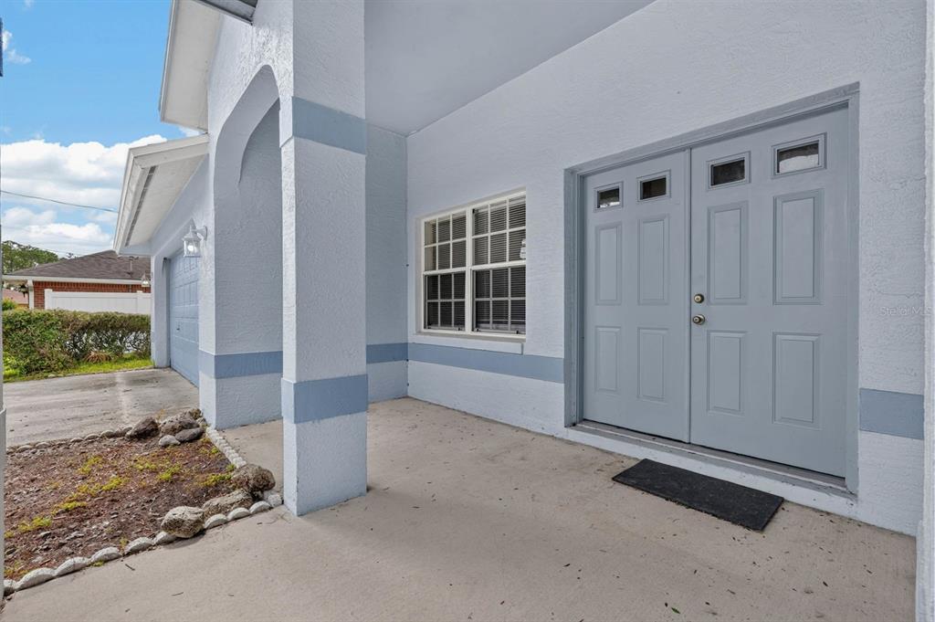 A covered entryway features a light blue double door, a window, and a concrete porch — 22 PINELYNN LANE, PALM COAST, FL