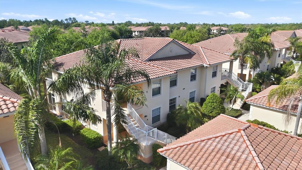 An aerial view shows multi-story apartment buildings with terracotta tile roofs and palm trees — 4266 VICENZA DRIVE UNIT A39, VENICE, FL