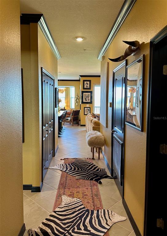 A hallway with yellow walls, dark doors, and zebra-print rugs leads to a living area — 17565 OPAL SAND DRIVE UNIT 405, VENICE, FL