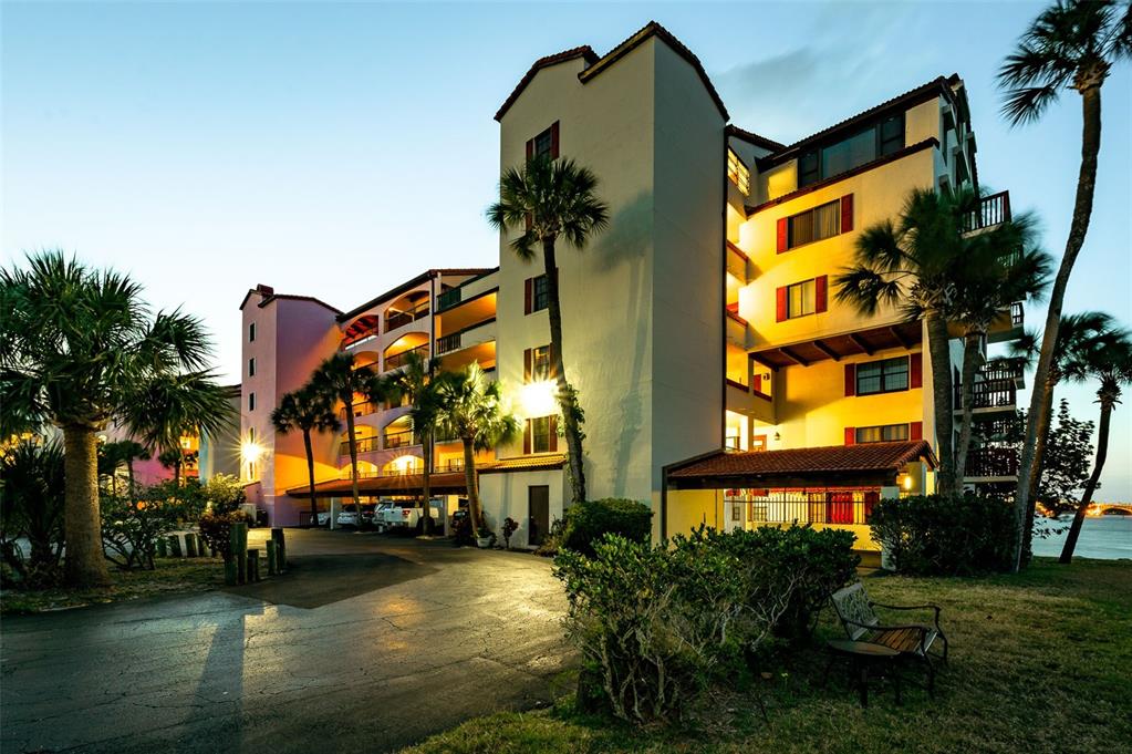 Exterior view of a multi-story apartment building with palm trees at dusk — 732 MARINA POINT DRIVE UNIT 7320, DAYTONA BEACH, FL