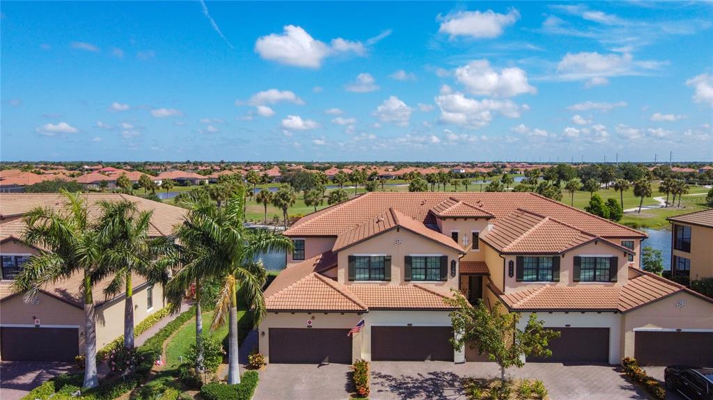 An aerial view of a multi-unit residential building with a tile roof and garages — 10796 TARFLOWER DRIVE UNIT 101, VENICE, FL