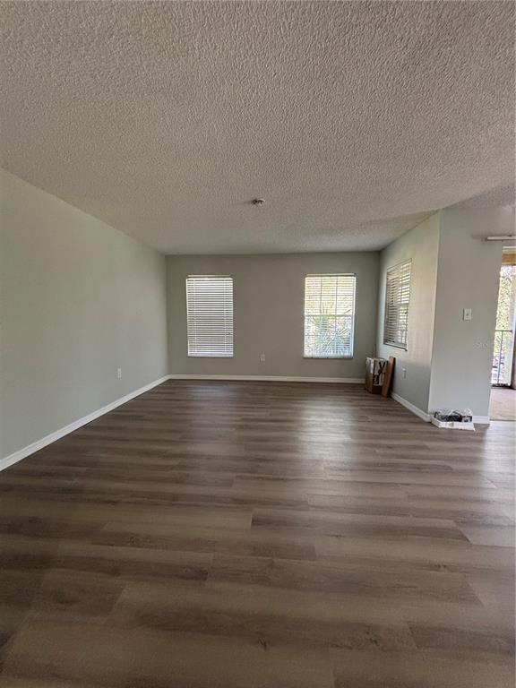 An empty living room features light gray walls, wood-look flooring, and two windows with blinds — 2690 CORAL LANDINGS BOULEVARD UNIT 535, PALM HARBOR, FL