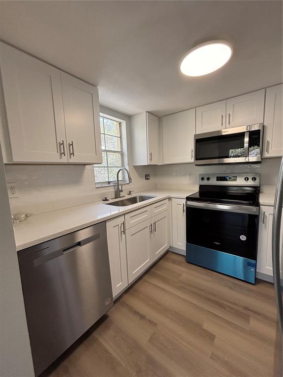 A kitchen with white cabinets, stainless steel appliances, quartz countertops, and light wood-look flooring — 2690 CORAL LANDINGS BOULEVARD UNIT 535, PALM HARBOR, FL