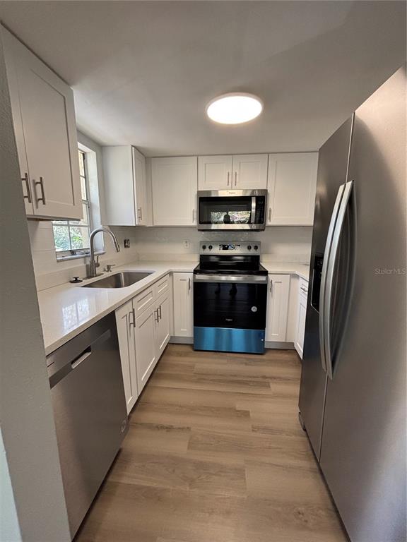 A modern kitchen features white cabinets, stainless steel appliances, and light wood-look flooring — 2690 CORAL LANDINGS BOULEVARD UNIT 535, PALM HARBOR, FL