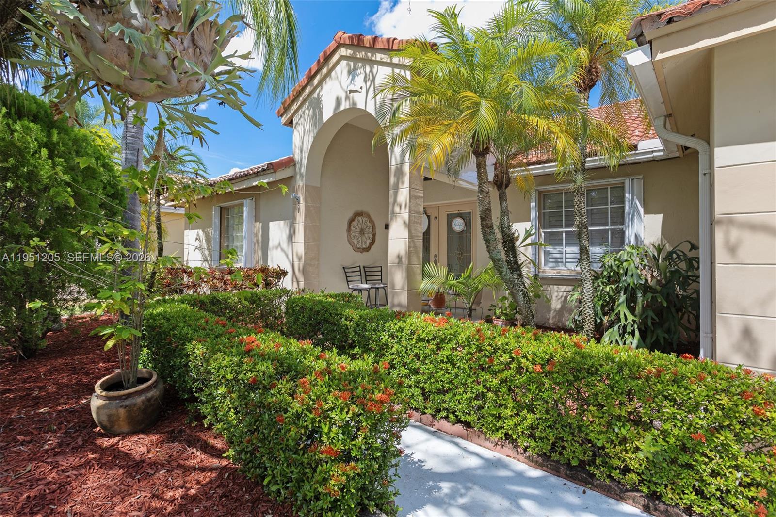 The exterior of a beige house features a tiled roof, arched entryway, and landscaped hedges — 798 Verona Lake Dr, Weston FL 33326, WESTON, FL