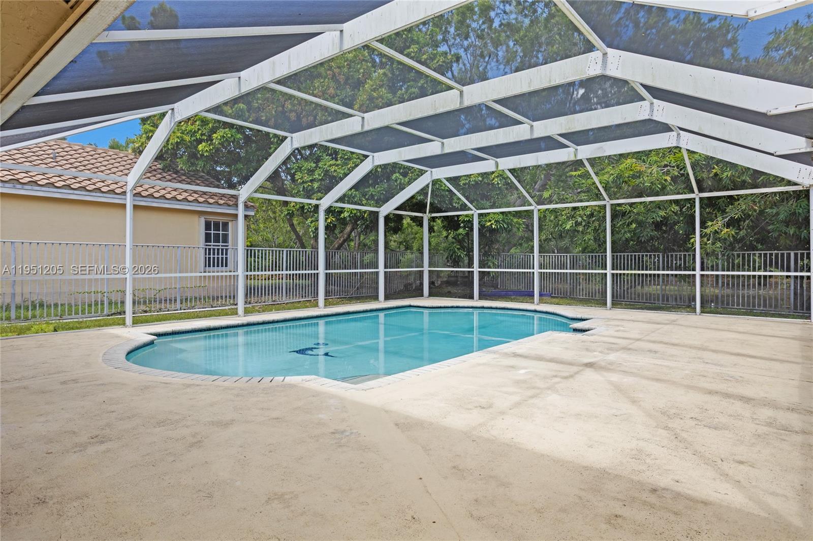 A swimming pool is enclosed by a white metal screen cage on a concrete patio — 798 Verona Lake Dr, Weston FL 33326, WESTON, FL