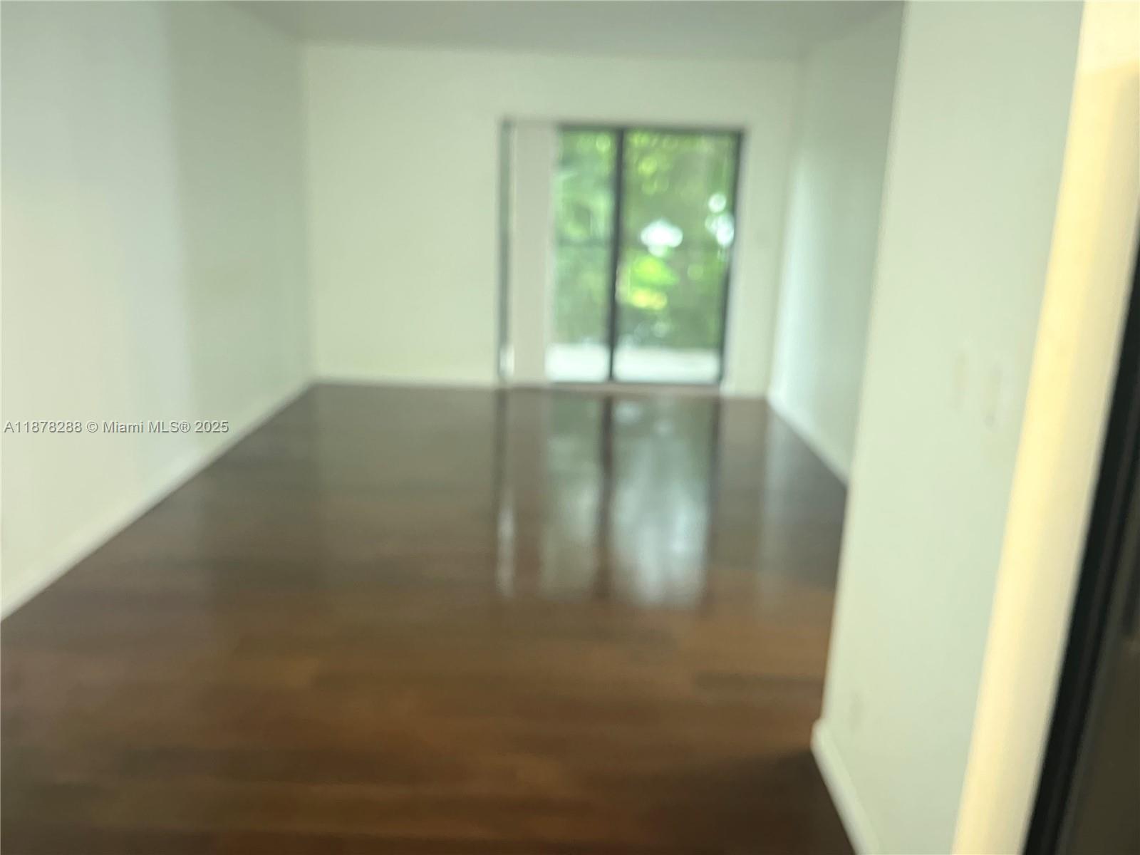 An empty room features dark hardwood flooring and a sliding glass door leading outside — 3720 N Pine Island Rd # 331, Sunrise FL 33351, SUNRISE, FL